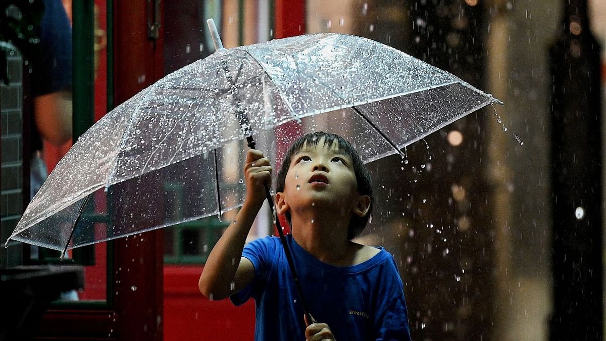 A boy uses an umbrella in Nanlouguxiang Alley during a rainfall in Beijing. Credit: AFP Photo