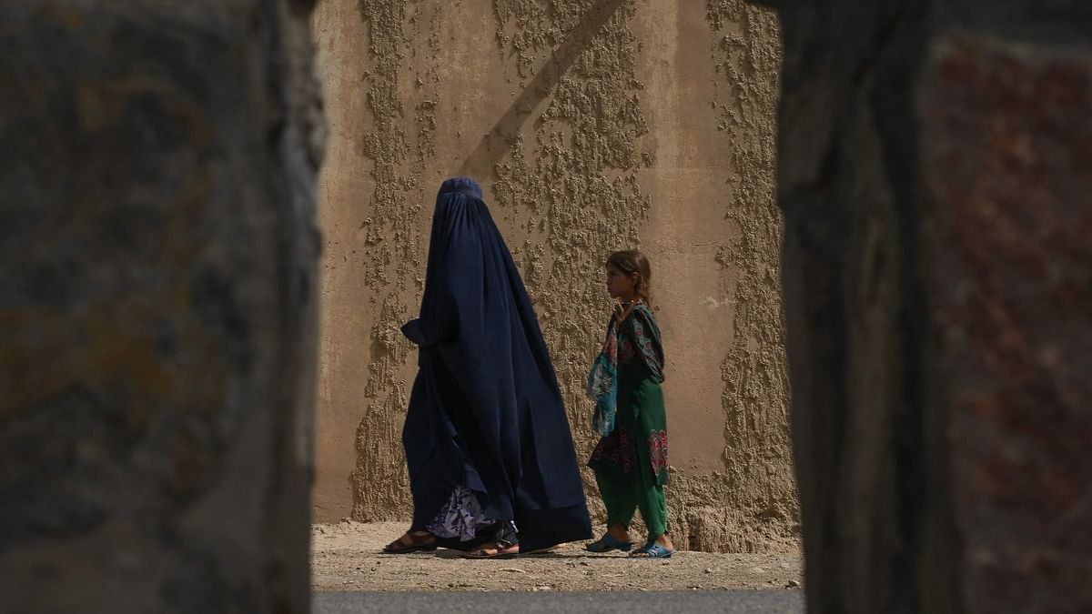 An Afghan woman walks with a child alongside a road in Kandahar. Credit: AFP Photo