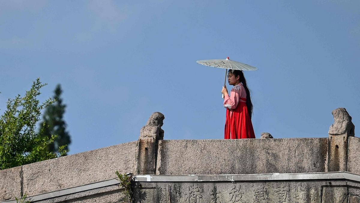 A woman wearing a costume protects herself from the sun with an umbrella in the Zhujiajiao ancient water town in Shanghai. Credit: AFP Photo