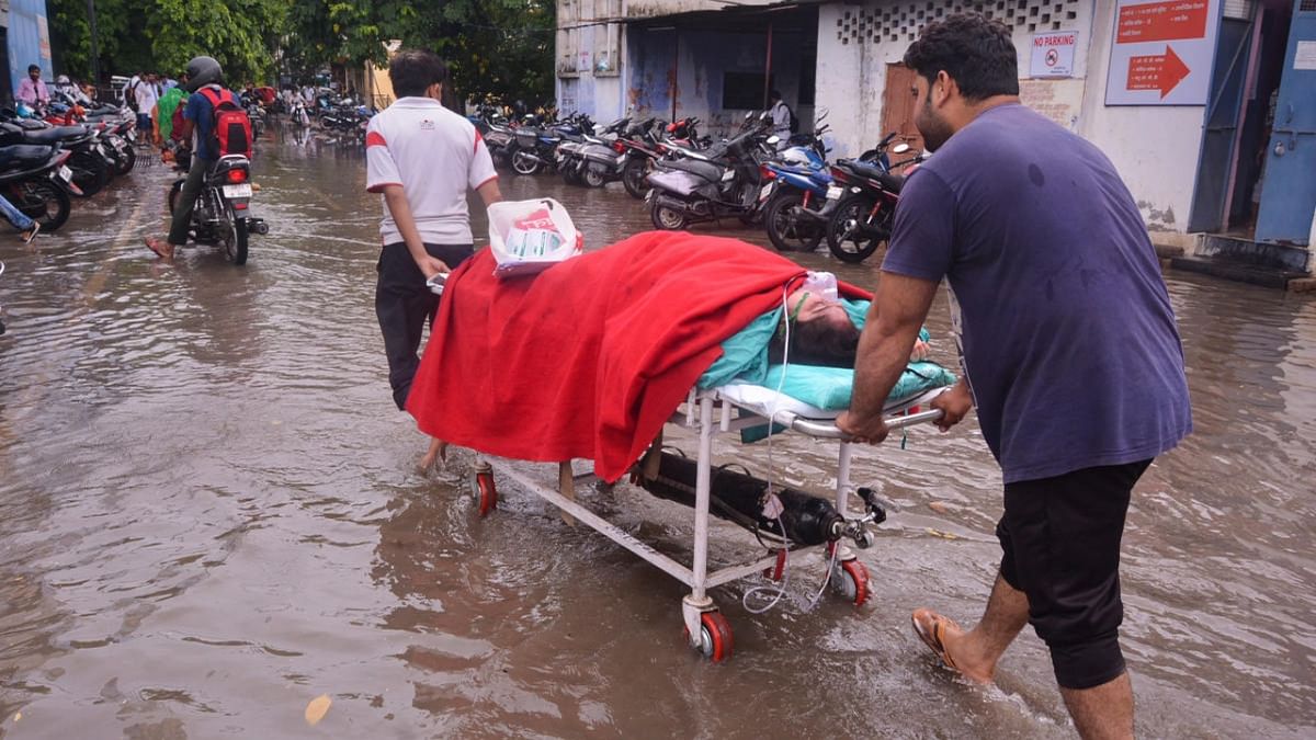 Workers assist a patient at the waterlogged premises of LLR hospital following monsoon rains, in Kanpur, Wednesday, August 3, 2022. Credit: PTI Photo