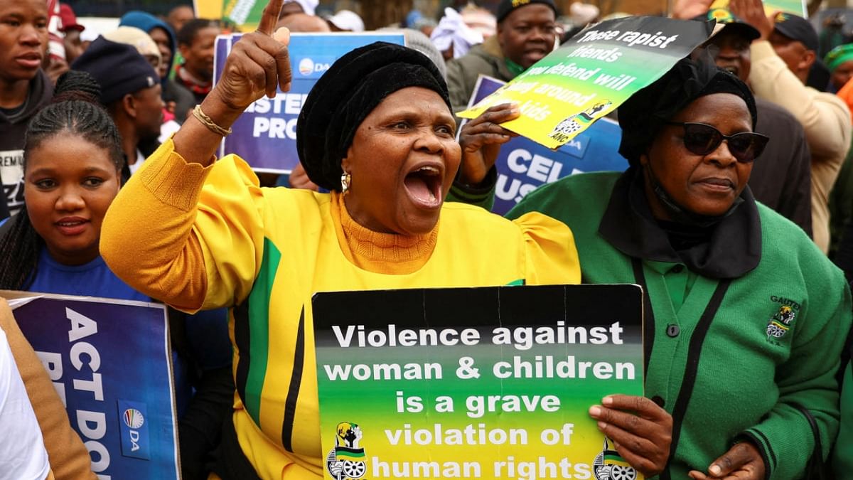 Protesters carry placards, as more than 80 men suspected of gang raping eight women and carrying out an armed robbery of a television crew appear in court in Krugersdorp, west of Johannesburg, South Africa, August 3, 2022. Credit: Reuters Photo