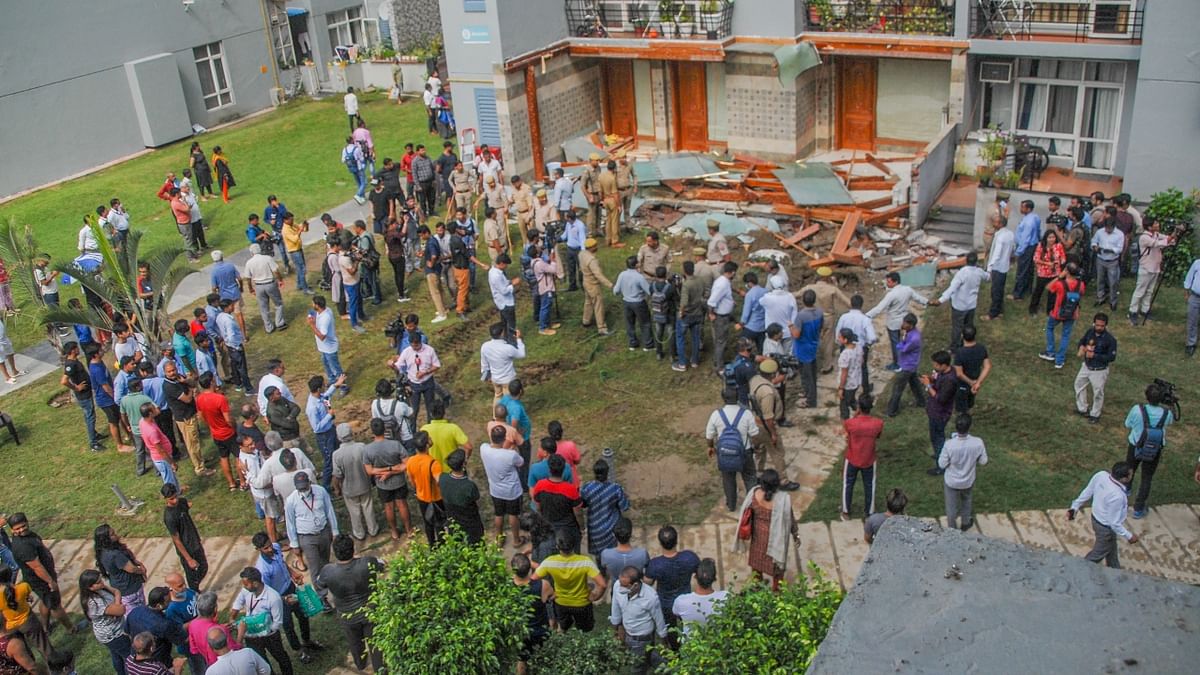 Residents gather as the Noida Authority demolishes illegal structures at the Grand Omaxe society, in Noida. Credit: PTI Photo