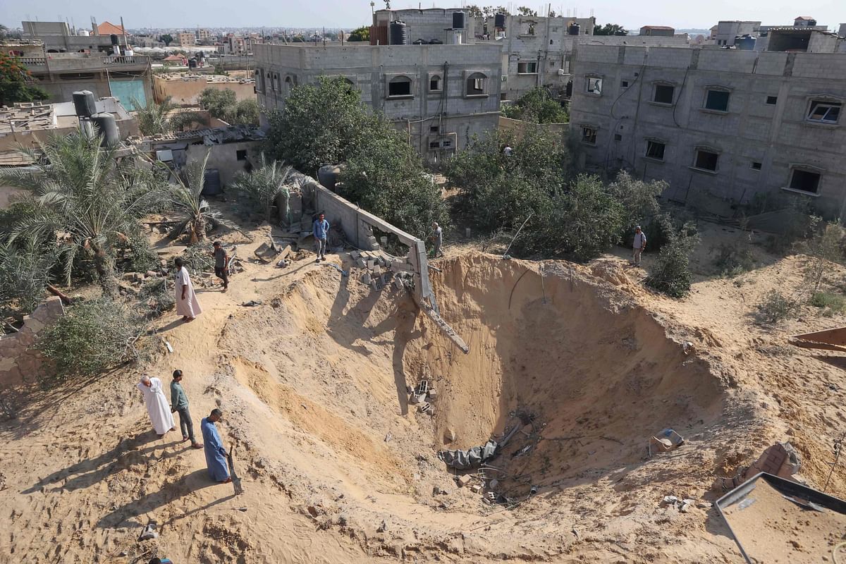 Palestinians inspect a crater following the latest three days of conflict with Israel ahead of a truce, in Rafah town in the southern Gaza Strip. Credit: AFP Photo