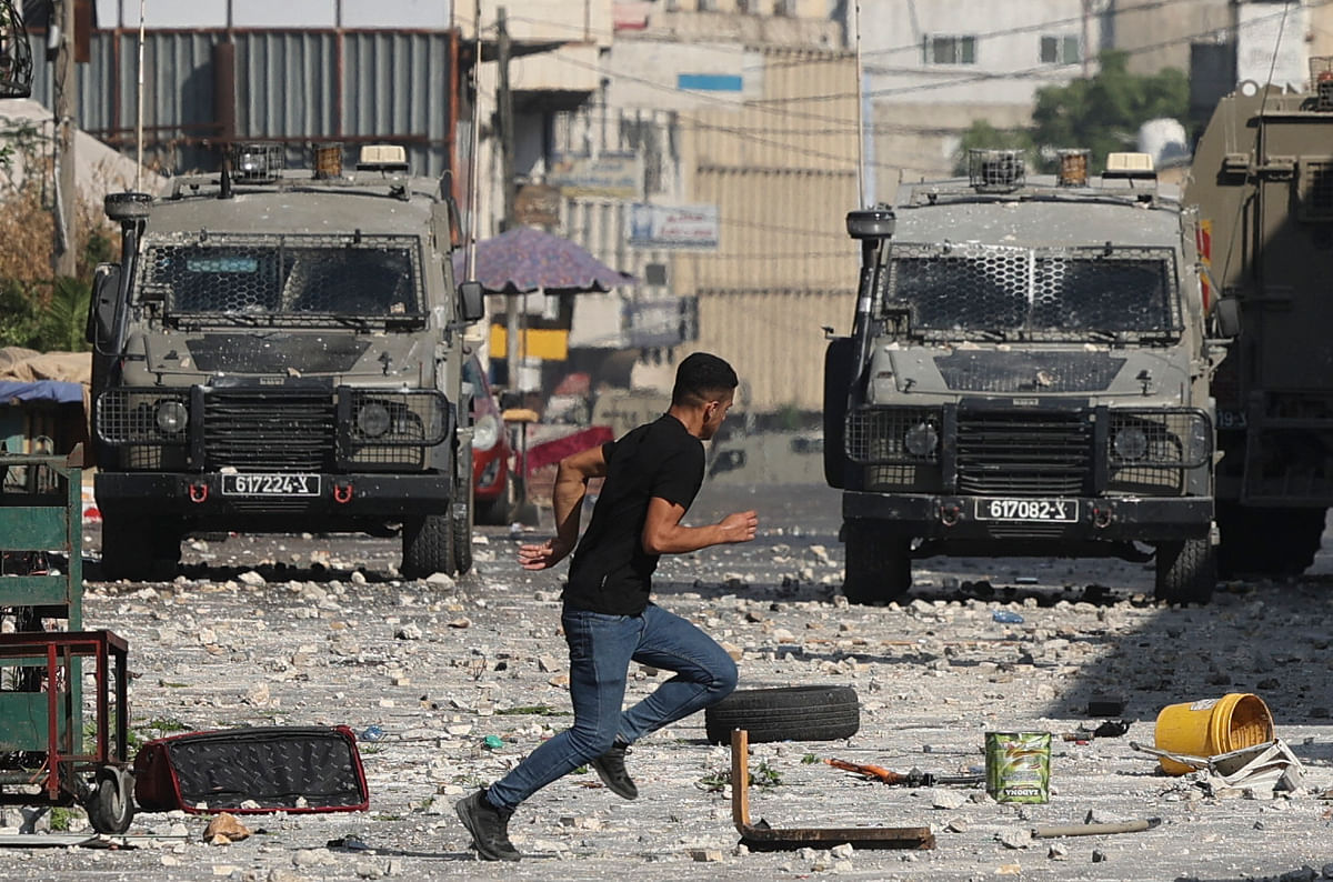 A Palestinian protester runs during clashes with Israeli security forces vehicles during their raid in the old town of Nablus, in the occupied West Bank. Credit: AFP Photo
