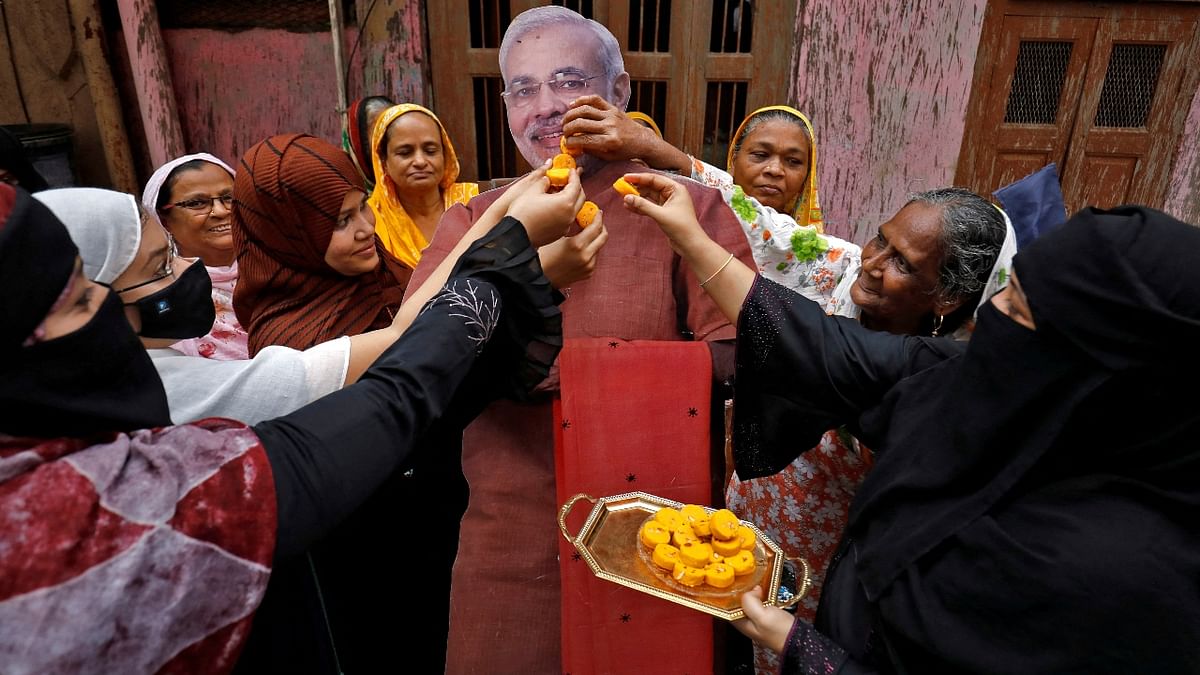 Muslim women offer sweets to a cardboard cut-out of Prime Minister Narendra Modi as they celebrate Raksha Bandhan, in Ahmedabad. Credit: Reuters Photo