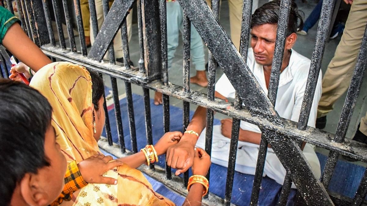 A sister ties 'rakhi' on the wrist of a brother who is lodged inside a jail, in Ajmer. Credit: PTI Photo