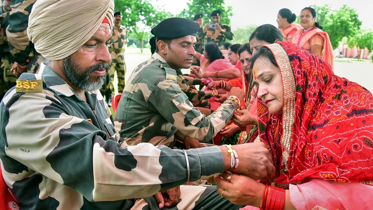 Women tie ‘rakhis’ on the wrists of BSF personnel on the occasion of the Raksha Bandhan, in Bikaner. Credit: PTI Photo