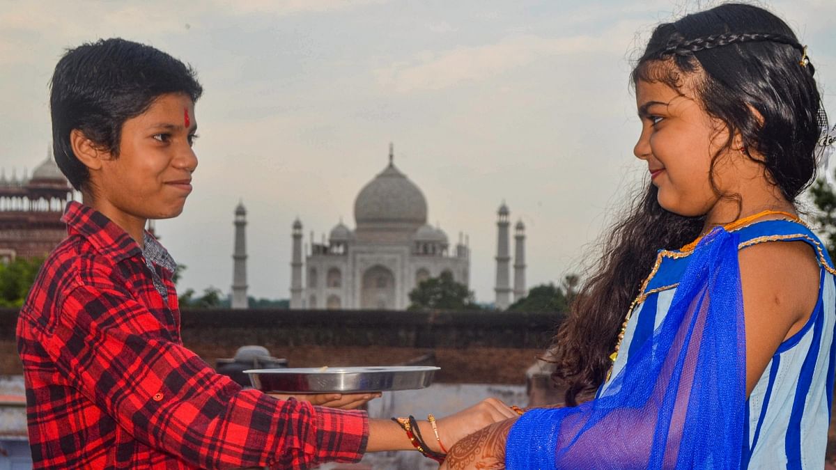 A sister ties 'rakhi' on the wrist of a brother on the 'Raksha Bandhan' festival in the backdrop of the historic Taj Mahal, in Agra. Credit: PTI Photo