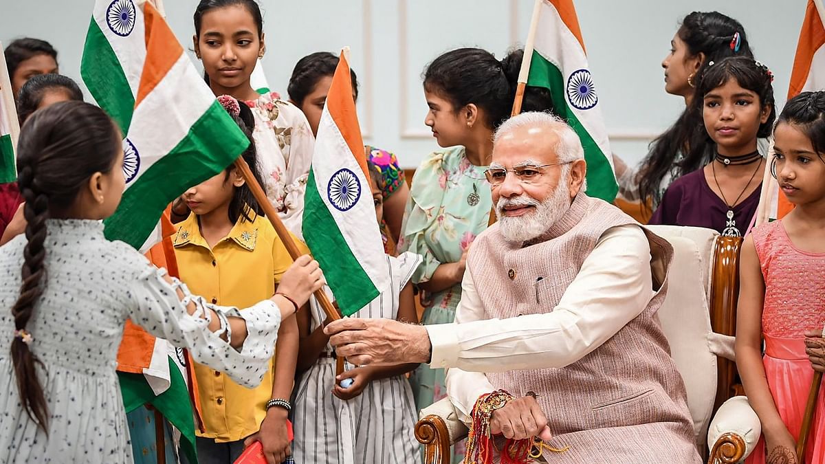 Prime Minister Narendra Modi hands over a 'tricolour' to a girl who tied a rakhi to him during Raksha Bandhan celebrations in New Delhi. Credit: PMO
