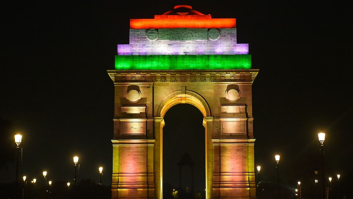 People visit the India Gate, illuminated with tricolour lights as part of 'Azadi ka Amrit Mahotsav' celebrations, ahead of Independence Day, in New Delhi. Credit: PTI Photo