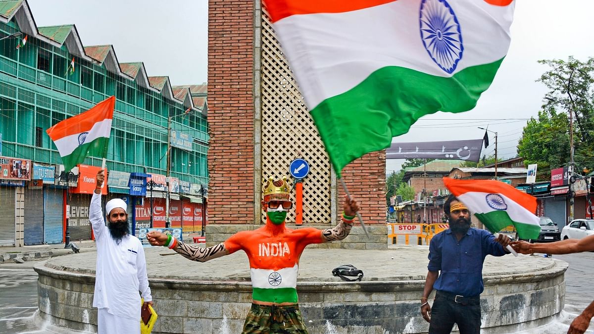 People wave the tricolour celebrating the 76th Independence Day, at Ghanta Ghar Lal Chowk in Srinagar. Credit: PTI Photo
