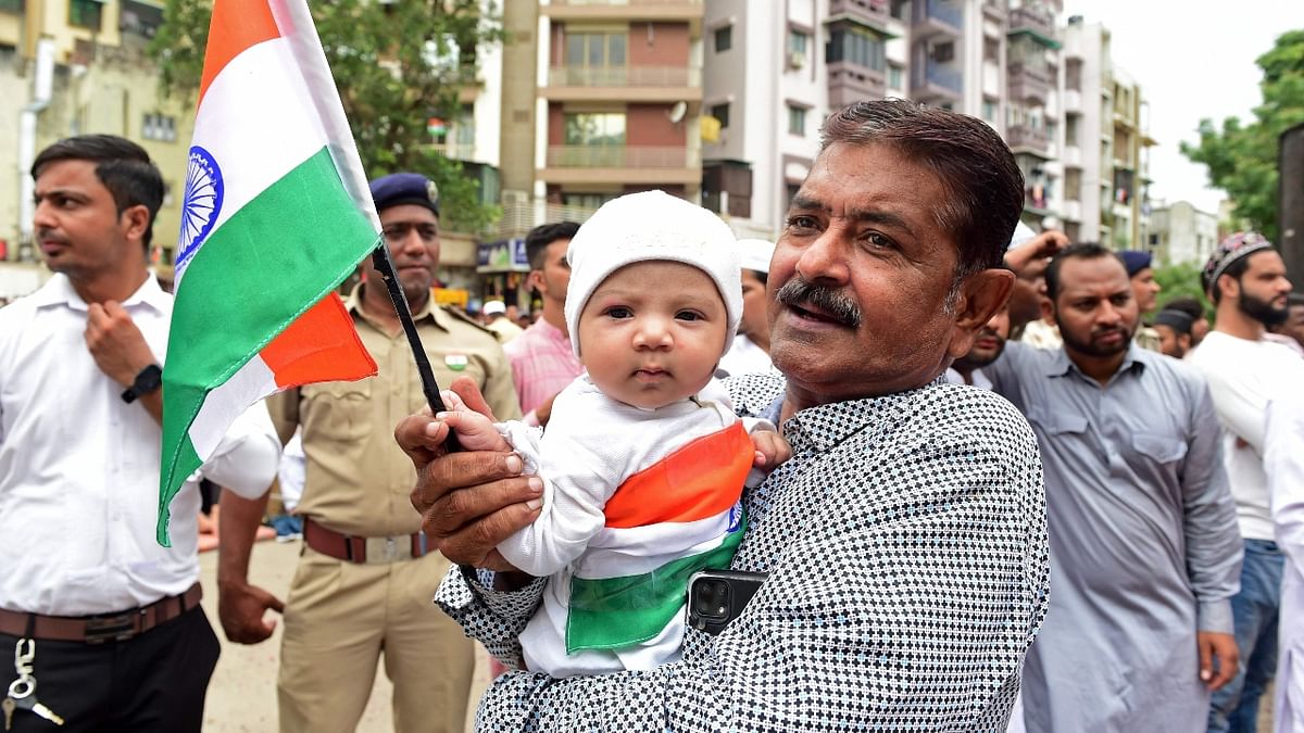 A man carries a child while holding an Indian national flag during the celebrations to mark country's 75th Independence Day in Ahmedabad. Credit: AFP Photo