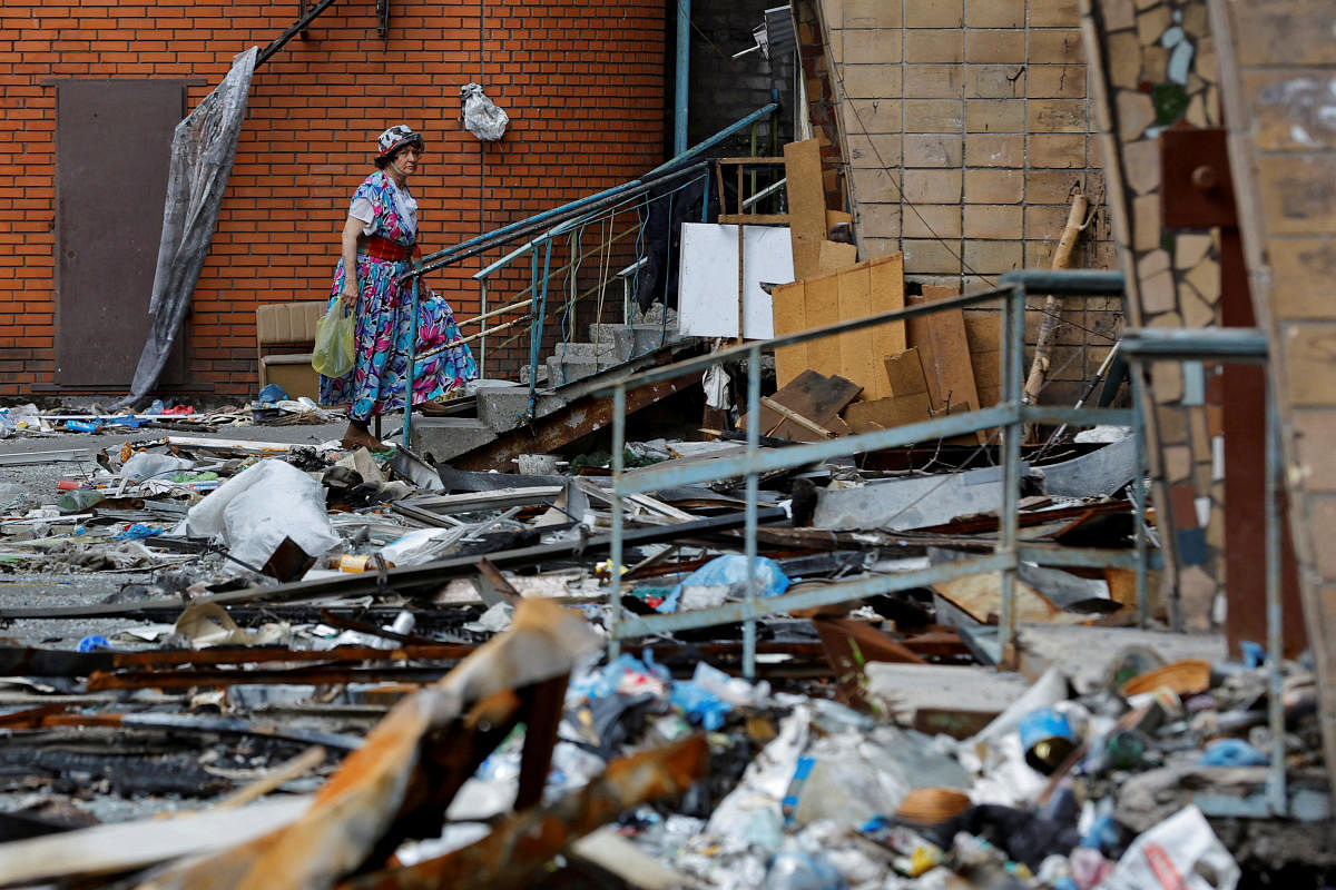 A woman walks outside an apartment building damaged in the course of Ukraine-Russia conflict in the southern port city of Mariupol, Ukraine. Credit: Reuters Photo