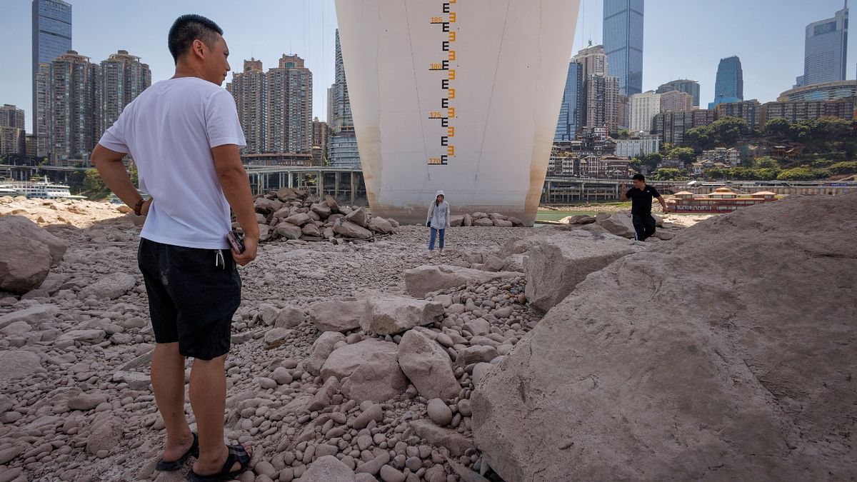 Locals stand by the central pillar of Qiansimen bridge that stands exposed on the dried-up riverbed of the Jialing river, a tributary of the Yangtze, that is approaching record-low water levels in Chongqing, China. Credit: Reuters Photo