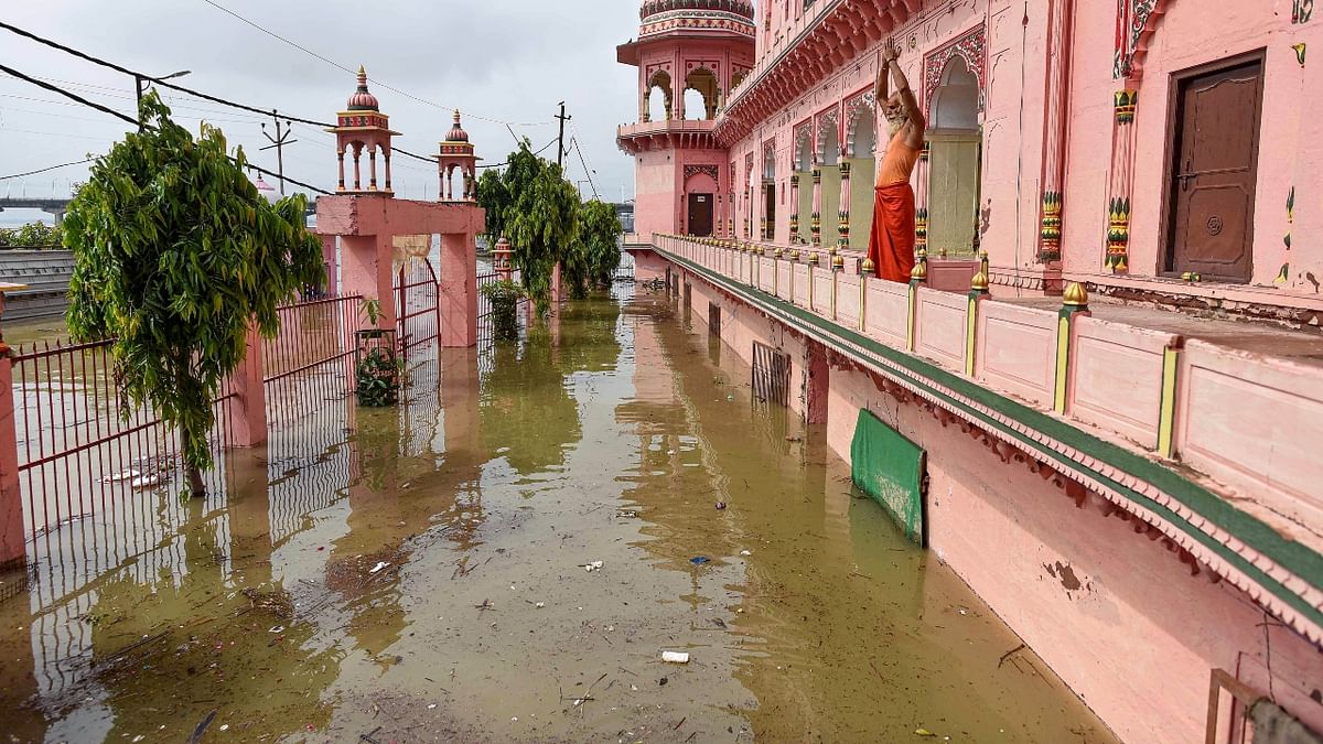 A priest offers prayers from a temple partially submerged in flood water, in Prayagraj. Credit: PTI Photo