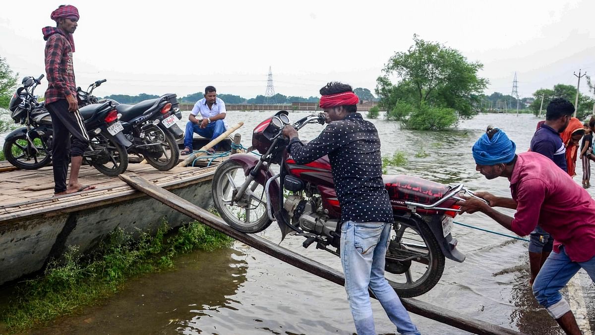 Villagers load their motorcycles in a boat as they move to a safe place in Prayagraj. Credit: PTI Photo