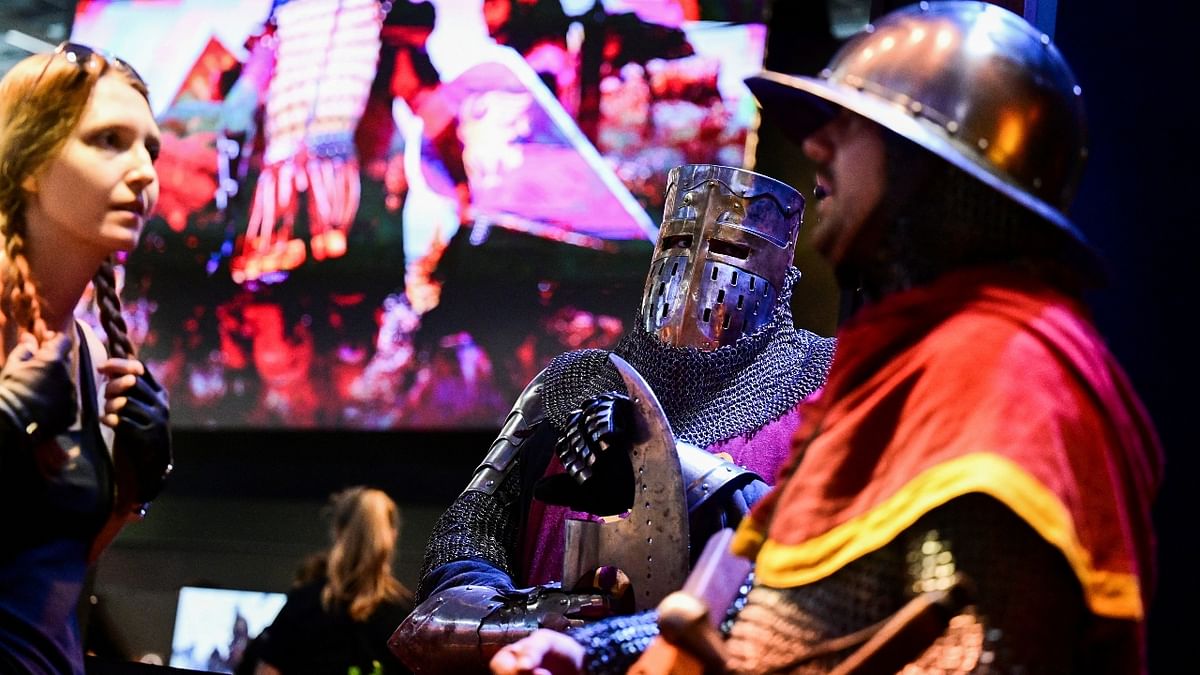 Two men in medieval armour pose in-front of a huge screen showing battle-scenes from the video-game Mount and Blade 2 Bannerlord at the Gamescom 2022. Credit: Reuters Photo