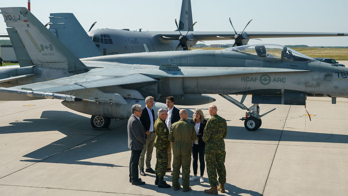 Canada's Prime Minister Justin Trudeau speaks with NATO Secretary General Jens Stoltenberg and Canada's Foreign Affairs Minister Melanie Joly near a Canadian Forces CF-18 Hornet fighter aircraft during their visit to CFB Cold Lake in Cold Lake, Alberta, Canada August 26, 2022. Credit: Reuters Photo