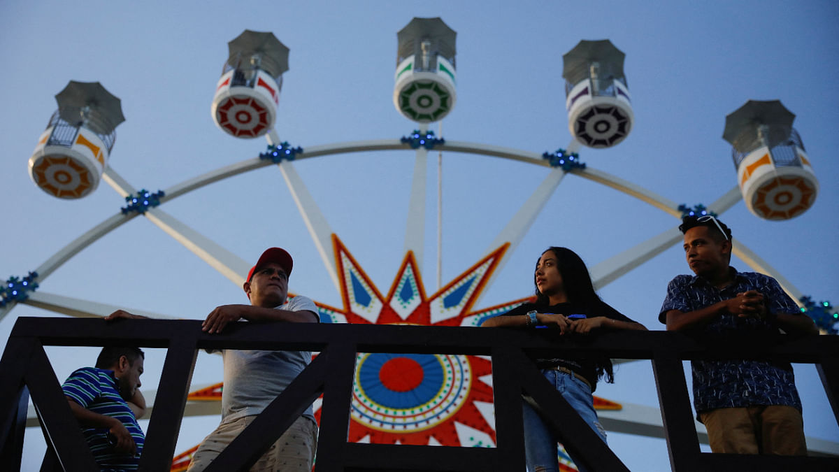 Visitors stand in front of a Ferris wheel during the opening day of Sunset Park, an amusement park financed by China, in La Libertad, El Salvador August 27, 2022. Credit: Reuters Photo