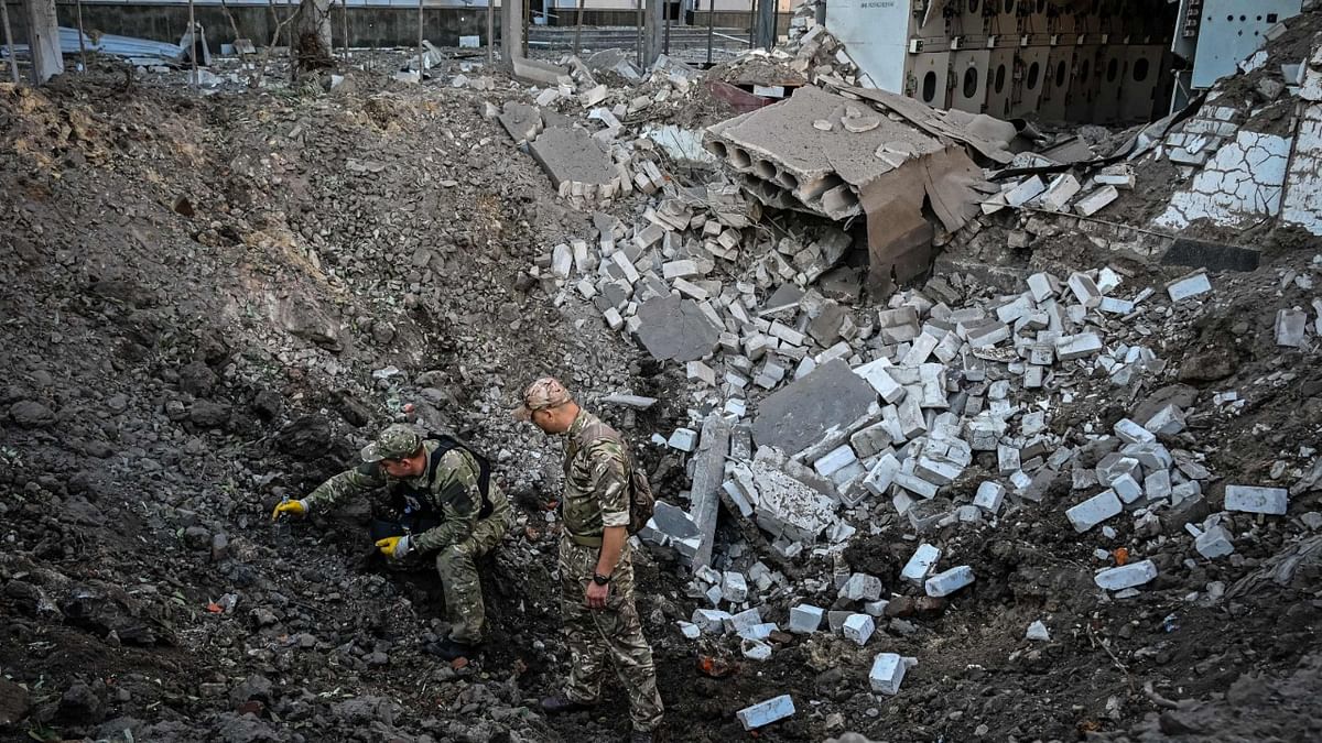 Ukrainian servicemen examine a crater following a missile strike in centre of Kharkiv on September 2, 2022, amid the Russian invasion of Ukraine. Credit: AFP Photo