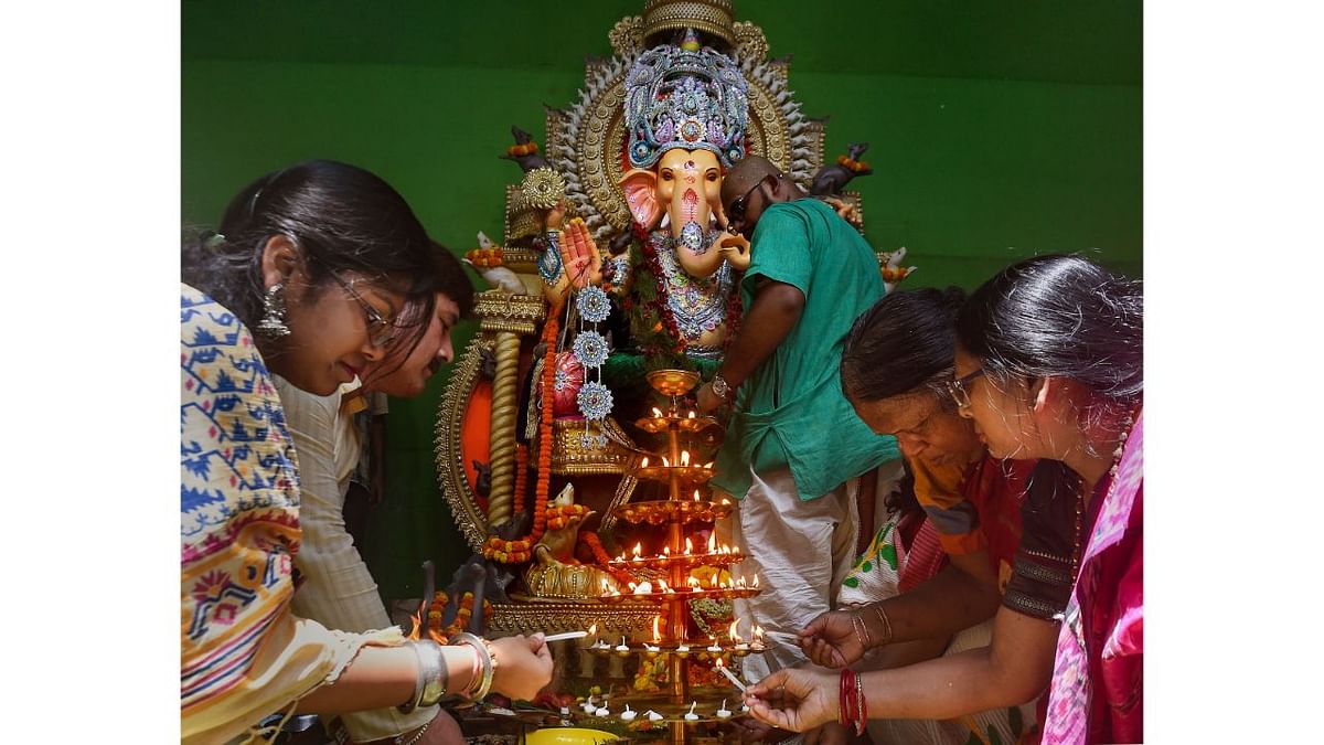 Devotees perform rituals before clay idols of Lord Ganesha at a community puja pandal during Ganesh Chaturthi in Kolkata. Credit: PTI Photo