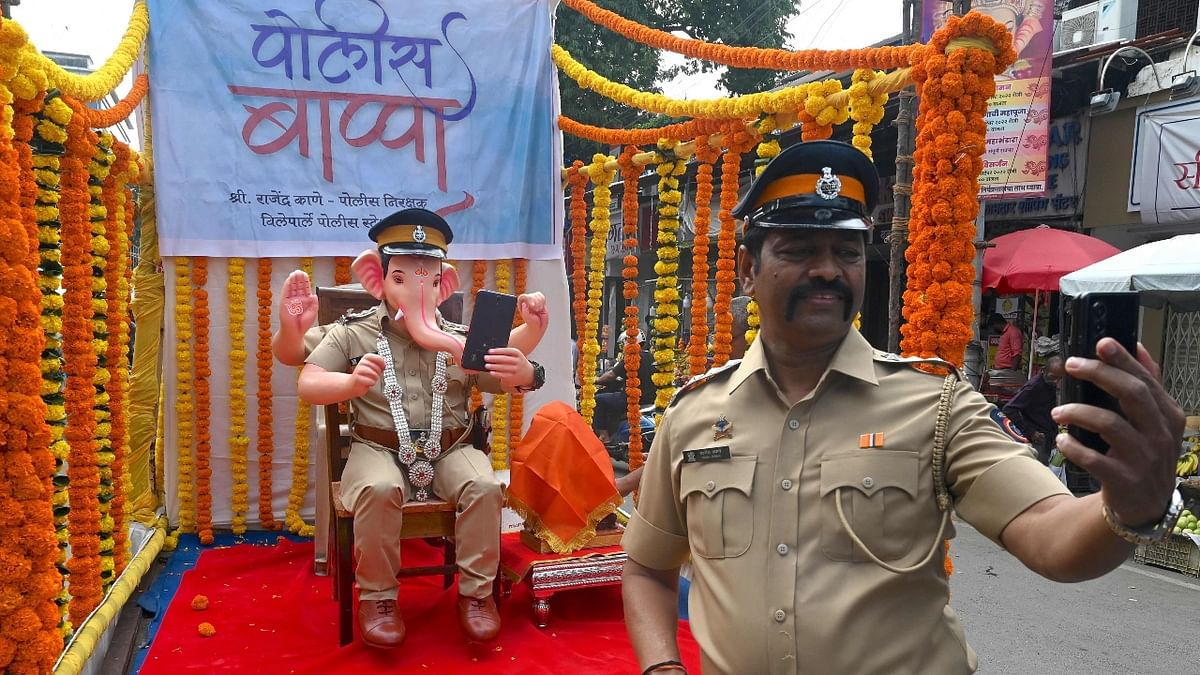 A policeman takes a selfie with an idol of Lord Ganesha in the avatar of a policeman during the Ganesh Chaturthi festival in Mumbai. Credit: AFP Photo