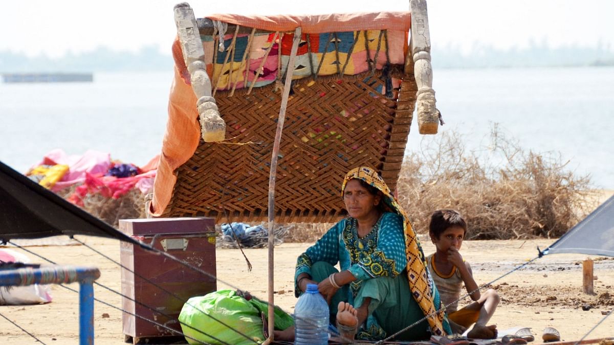 A flood-affected woman sits with her child under the shade of a charpai at a makeshift camp in Dera Allah Yar town in Jaffarabad district, Balochistan province. Credit: AFP Photo