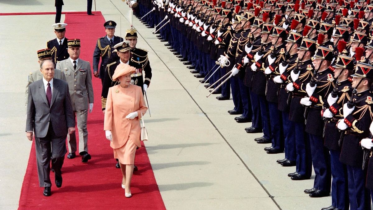 Queen Elizabeth II reviews an honour guard accompanied by French President Francois Mitterrand upon her arrival at Orly airport in France in 1992. Credit: AFP Photo