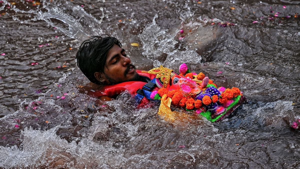 A devotee immerses an idol of Lord Ganesha in an artificial pond on the last day of the Ganesh Chaturthi festival, in Ajmer. Credit: PTI Photo