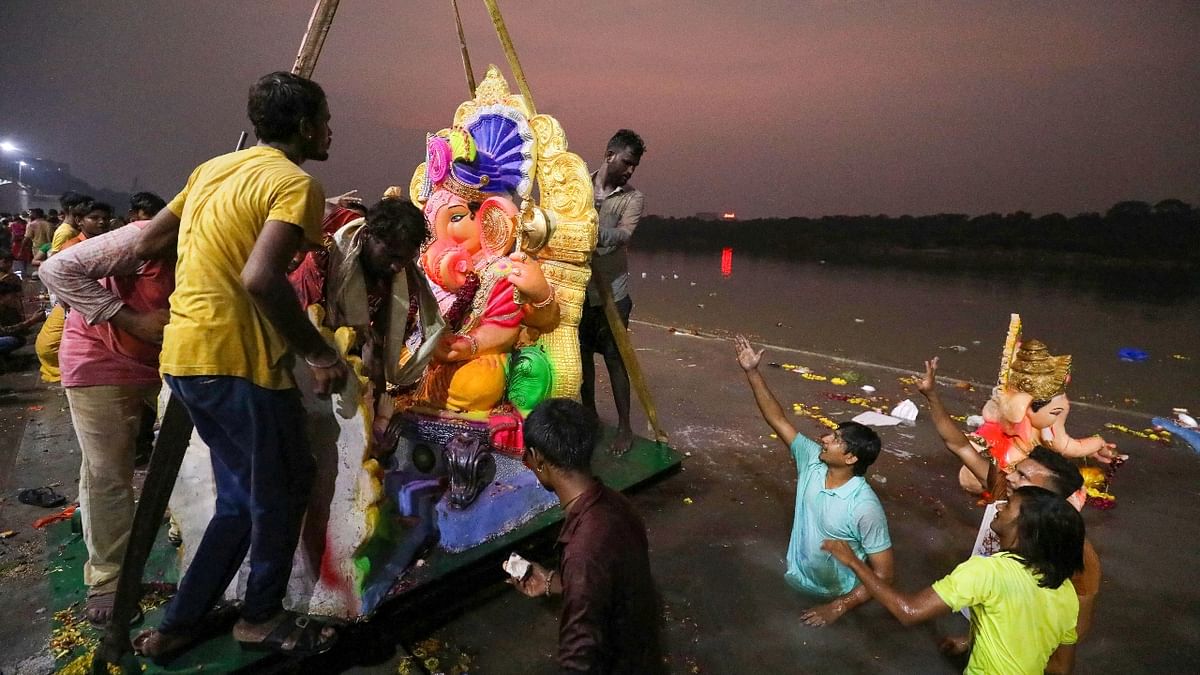 A crane lowers an idol of Lord Ganesha into a pond on the last day of the Ganesh Chaturthi festival, in Ahmedabad. Credit: PTI Photo