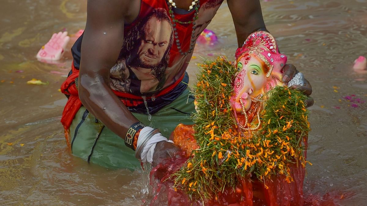 A volunteer immerses an idol of Lord Ganesha in an artificial pond on the last day of Ganesh Chaturthi, in Delhi. Credit: PTI Photo