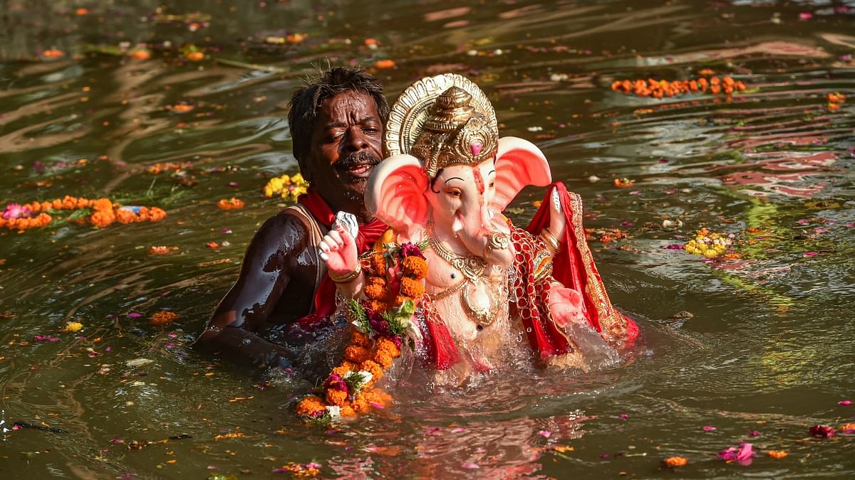 A devotee immerses an idol of Lord Ganesha in the Gomti river during Gauri Ganpati Visarjan, in Lucknow. Credit: PTI Photo