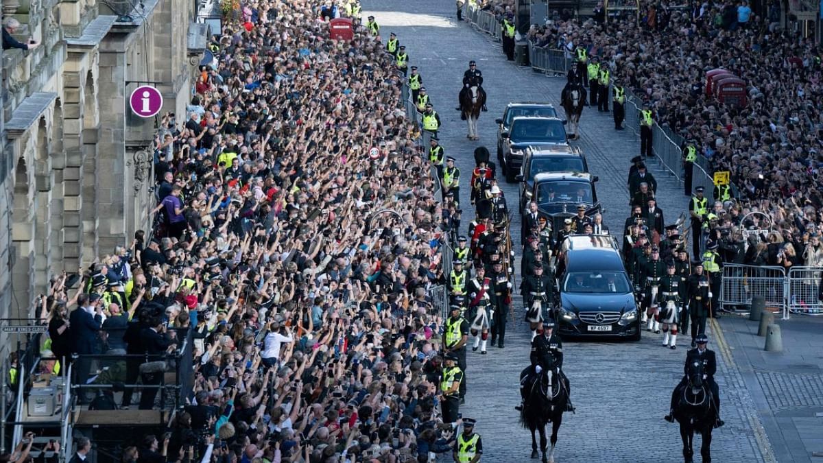 Members of the public watch the procession of the late Queen Elizabeth II's coffin, from the Palace of Holyroodhouse to St Giles Cathedral in Edinburgh, on the Royal Mile. Credit: AFP Photo