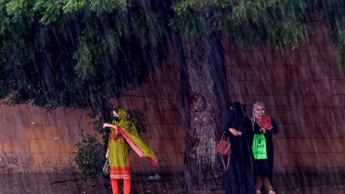 People wait to board a public transport along a street during heavy rainfalls in Karachi. Credit: AFP Photo