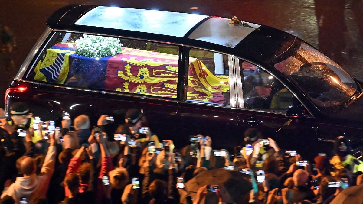 Many held their phones in the air to capture a photo of the coffin, still draped in the royal standard of Scotland, in the illuminated hearse. Credit: Reuters Photo