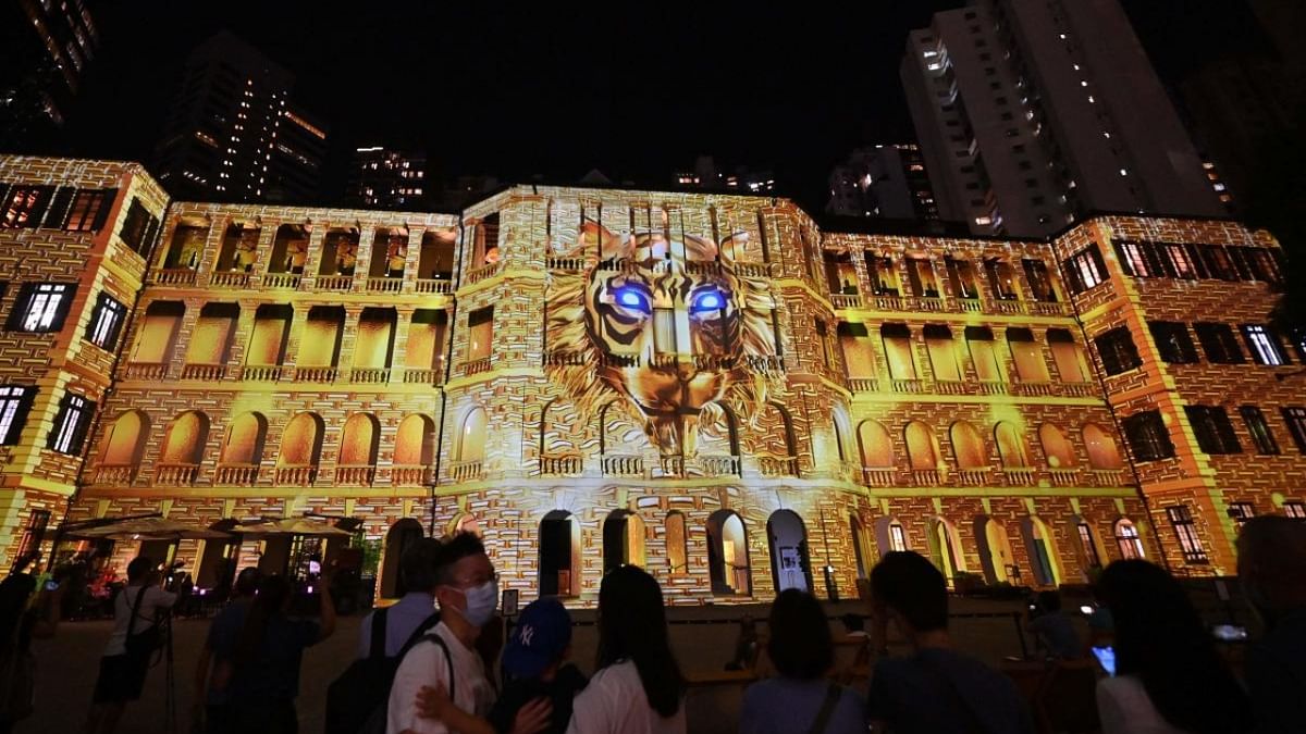 People watch a light show of animations and images projected on the facade of the Barrack Block of Tai Kwun, the historic former police headquarters compounds, in Hong Kong. Credit: AFP Photo