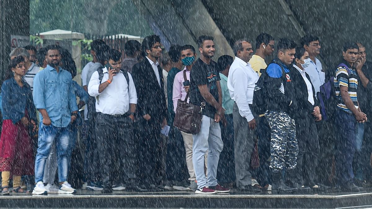 Commuters take shelter at the Mandi House metro station amid rainfall in New Delhi. Credit: PTI Photo