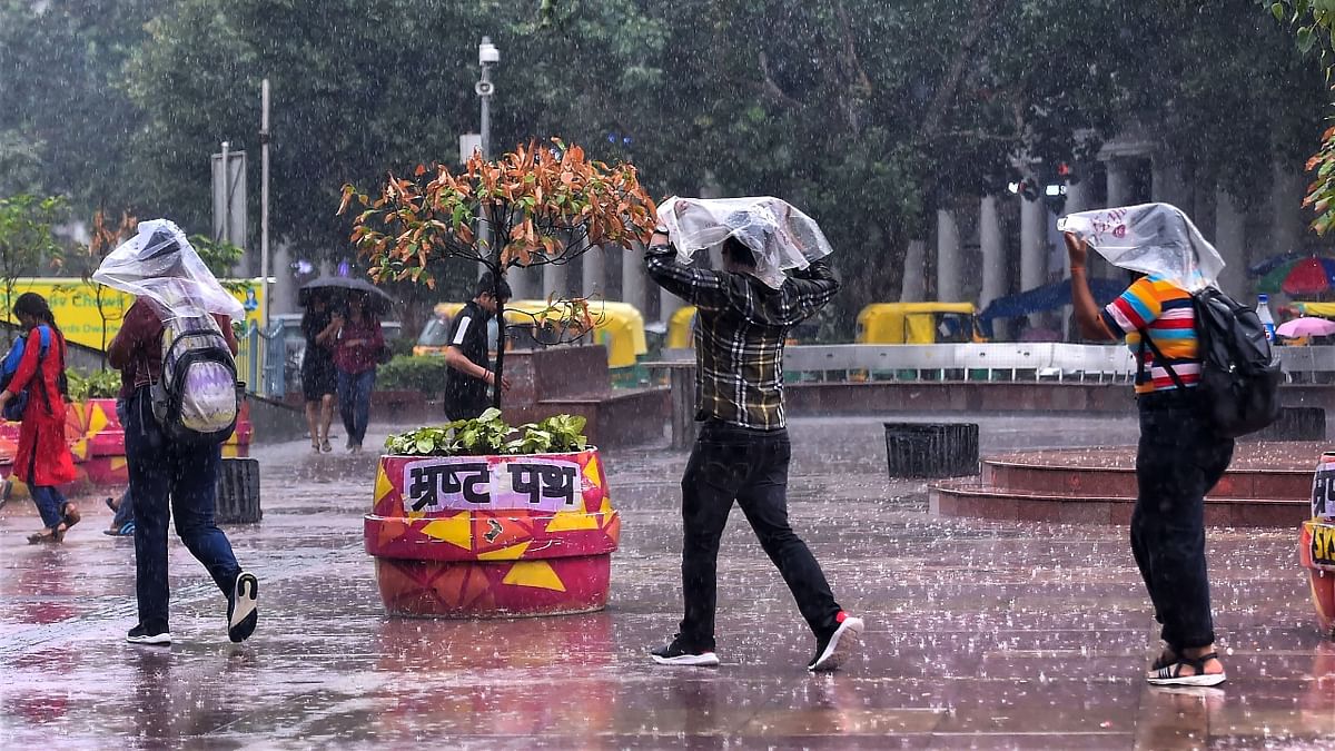 Pedestrians cover themselves with plastic sheets during heavy rains in New Delhi. Credit: PTI Photo