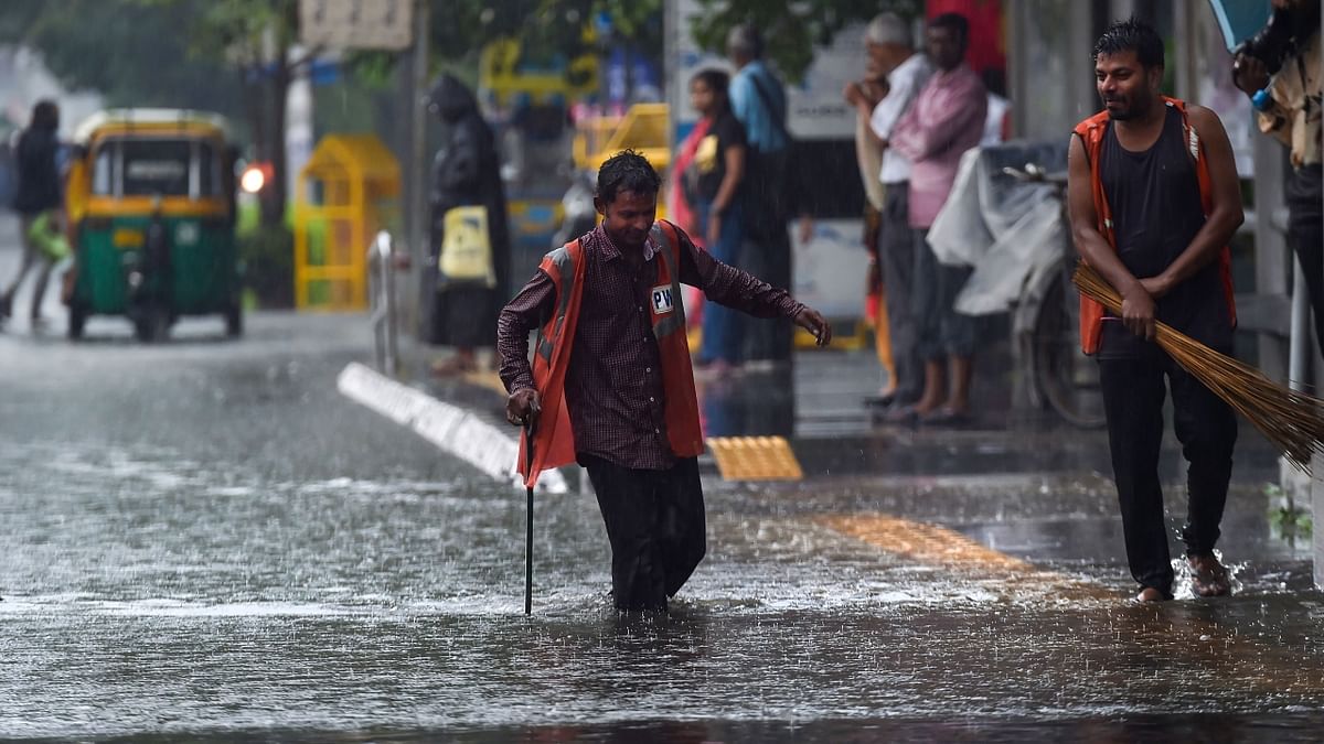 Civic body workers attempt to clear a waterlogged road after heavy rainfall at ITO in New Delhi. Credit: PTI Photo
