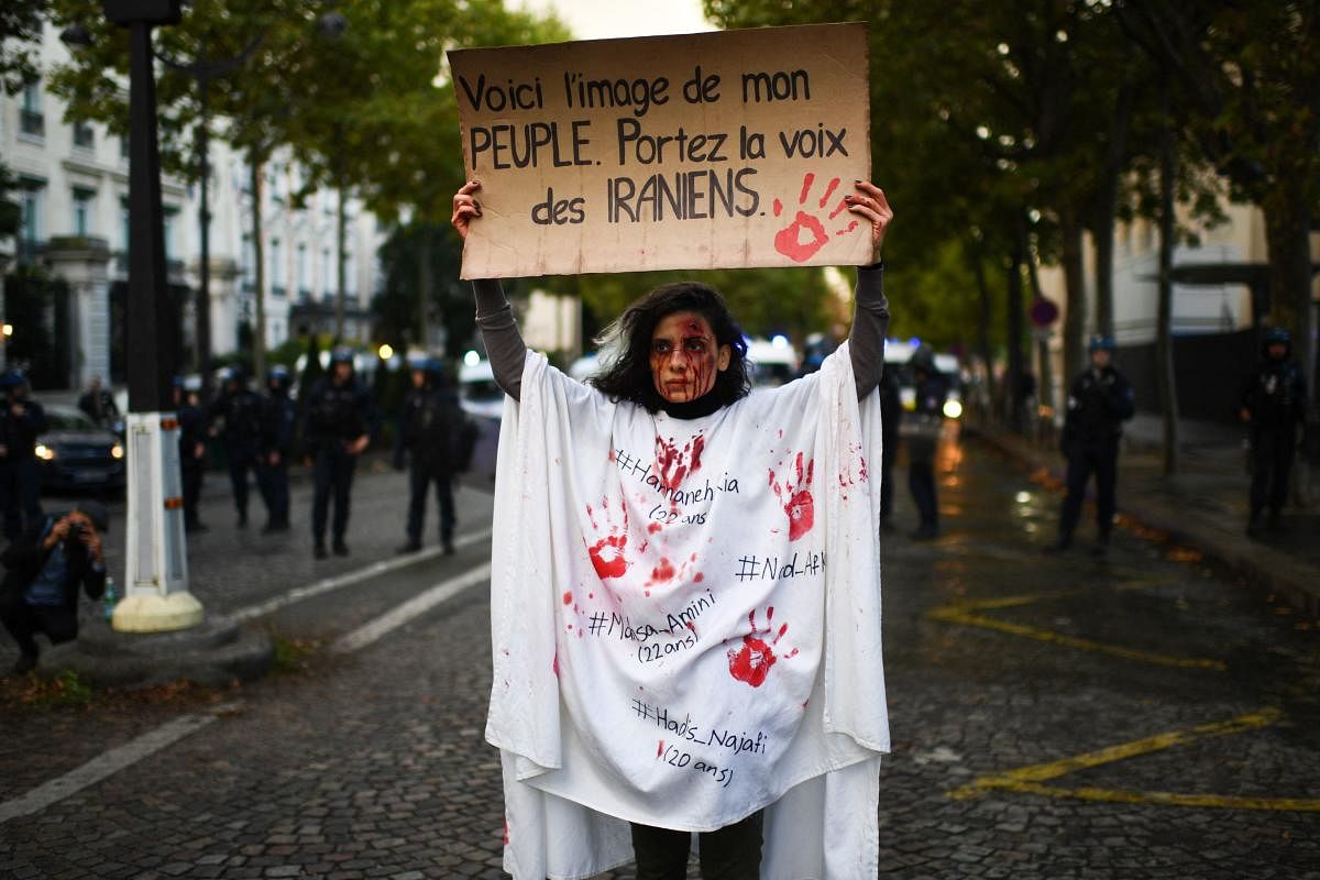 A protetor holds a banner reading 'This is the image of my people. Carry the voice of the Iranians' as she stands in front of riot police during a demonstration in support of Iranian protesters in Paris. Credit: AFP Photo