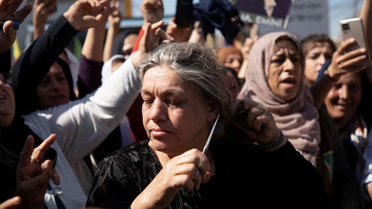 A woman cuts her hair during a protest over the death of 22-year-old Kurdish woman Mahsa Amini in Iran, in the Kurdish-controlled city of Qamishli, northeastern Syria. Credit: Reuters Photo