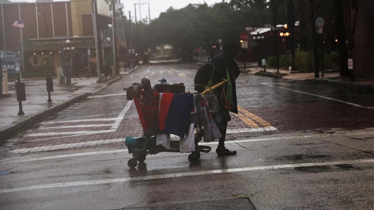 A man carries his belongings across the street as Hurricane Ian makes landfall in southwestern Florida, in the Ybor City section of Tampa. Credit: Reuters photo