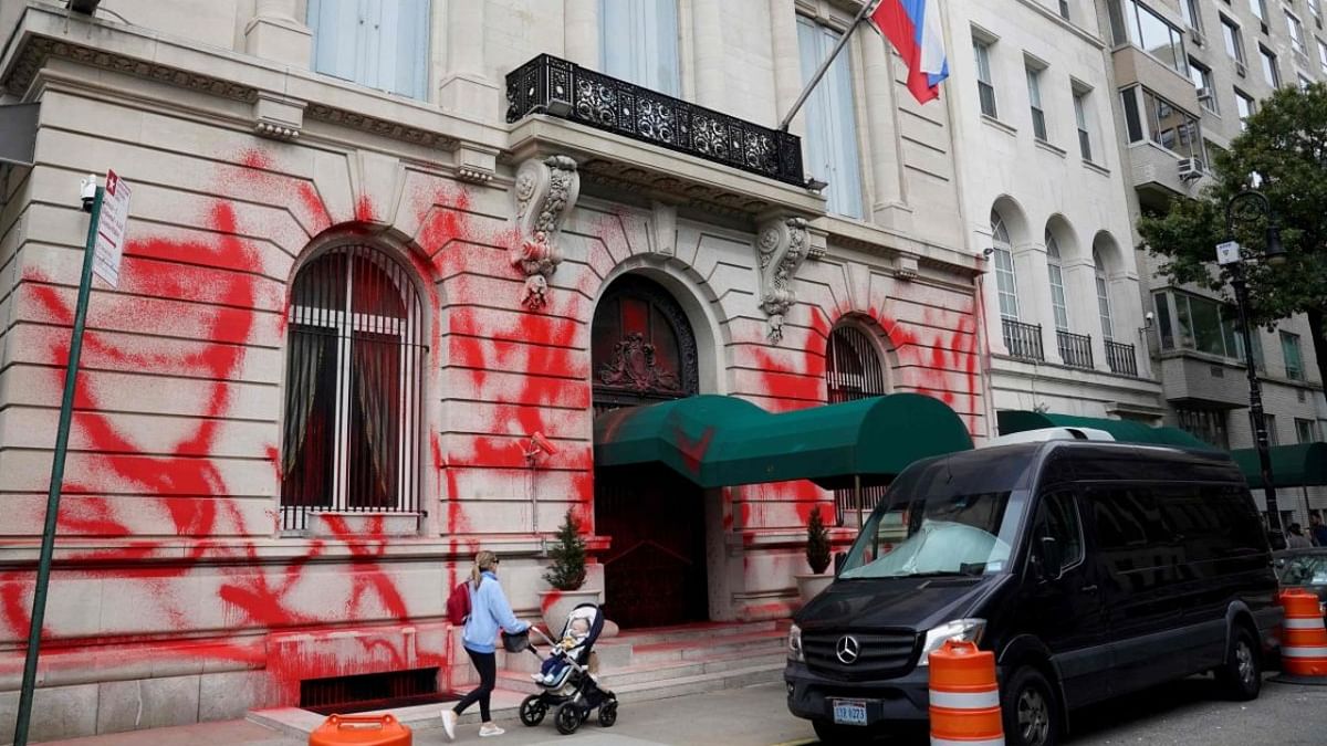 A woman pushes a child past the Russian consulate in New York on September 30, 2022 after it was vandalized with red spray paint early Friday in a possible bias incident, according to a spokesman for the New York Police Department. Credit: AFP Photo