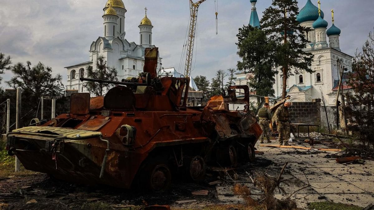 Ukrainian servicemen walk next to a destroyed Russian Army APC in a yard of Burial Shroud of the Mother of God Orthodox Church on the bank of the Seversky Donets River near the town of Sviatohirsk. Credit: AFP Photo