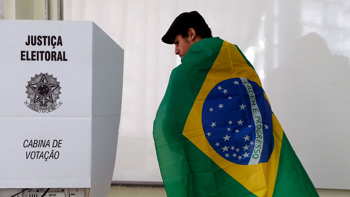 A man wrapped in a Brazilian flag prepares to cast his vote during the legislative and presidential election, in Sao Paulo, Brazil, on October 2, 2022. Credit: AFP Photo