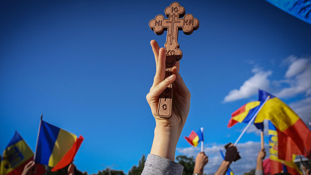A supporter of the Alliance for the Union of Romanians (AUR), a right-wing populist and nationalist party, holds up a wooden christian-orthodox cross, during a protest against the government and the price risings for energy and utilities, in Bucharest on October 2, 2022. Credit: AFP Photo