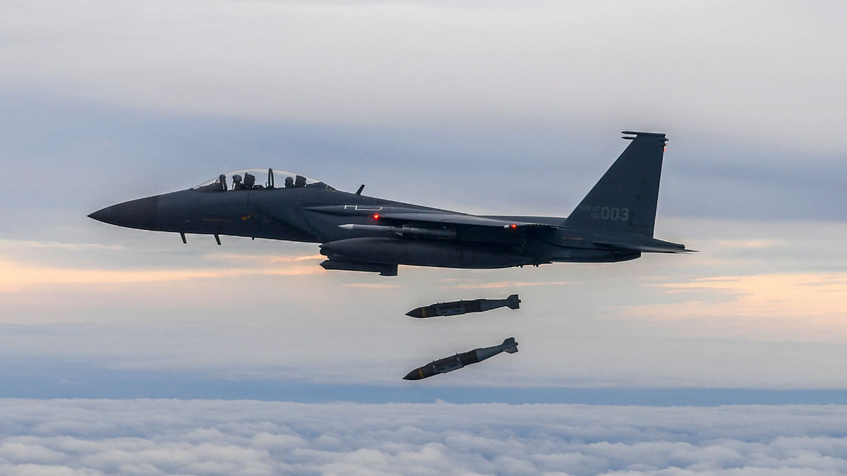 This handout photo taken on October 4, 2022 and provided by the South Korean Defence Ministry in Seoul shows a South Korean Air Force F-15K dropping two joint direct attack munition (JDAM) bombs against a target at the Jikdo shooting field in the Yellow Sea. Credit: AFP Photo