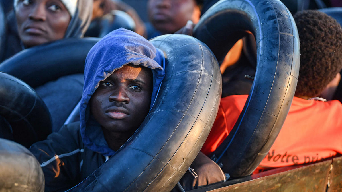Migrants from sub-Saharan Africa sit in a makeshift boat that was being used to clandestinely make its way towards the Italian coast, as they are found by Tunisian authorities about 50 nautical miles in the Mediterranean sea off the coast of Tunisia's central city of Sfax on October 4, 2022. Credit: AFP Photo