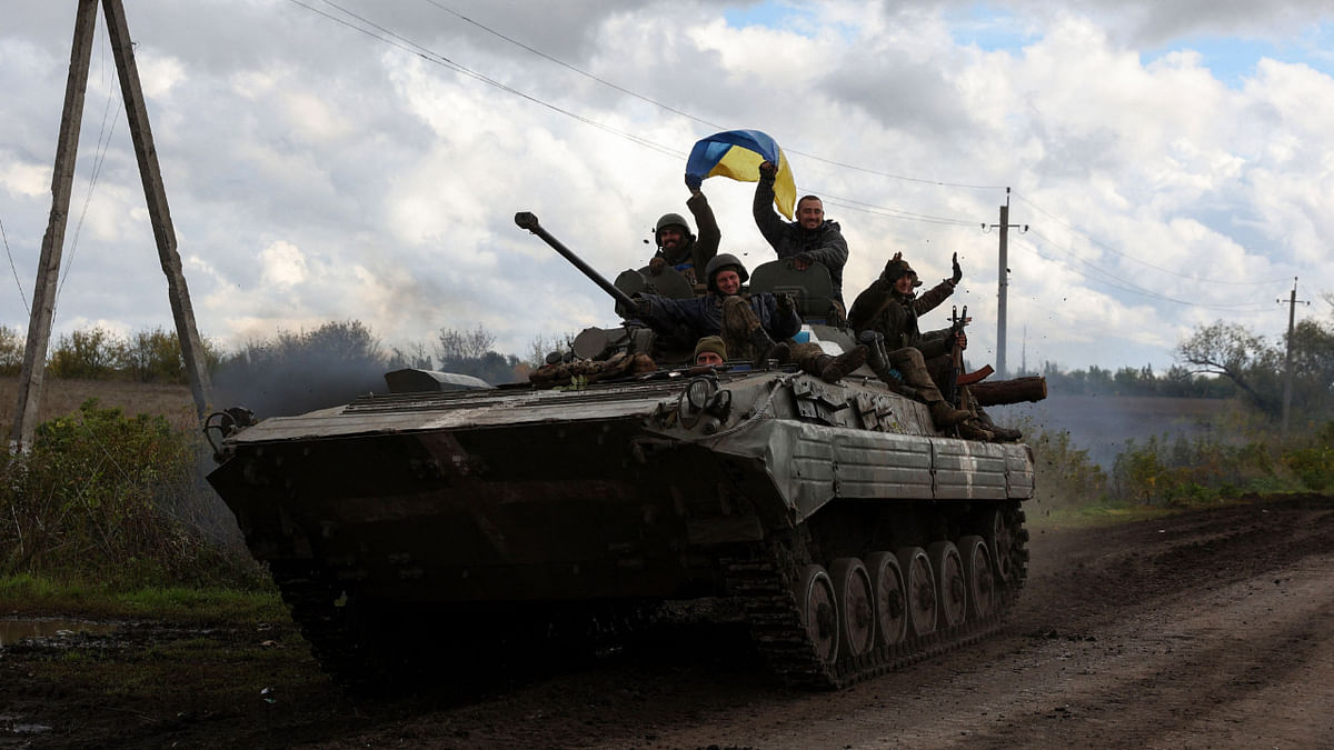 Ukrainian soldiers wave a national flag atop a personnel armoured carrier on a road near Lyman, Donetsk region on October 4, 2022, amid the Russian invasion of Ukraine. Credit: AFP Photo