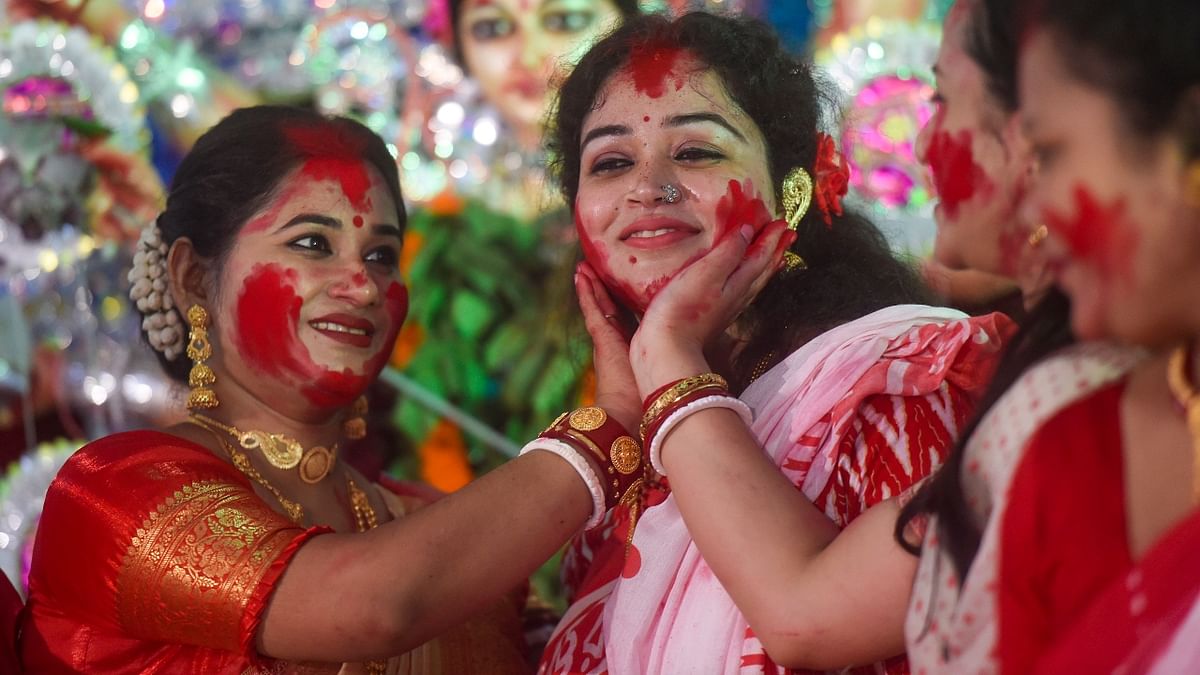 Married women apply vermillion on each other as they participate in 'Sindoor Khela' on the last day of Durga Puja festival celebrations, in New Delhi. Credit: PTI Photo